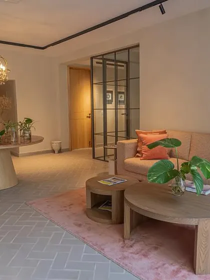 The waiting area of a modern office we designed, featuring our custom-made furniture. The space includes a comfortable sofa, nested wooden coffee tables, and a round pedestal table, all in soft, earthy tones.