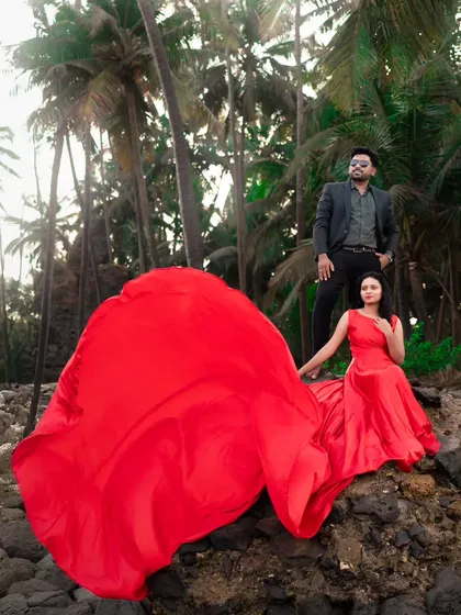 A movie-poster moment. The dramatic red trail of the gown billows in the wind, creating a stunning, cinematic shot for this pre-wedding couple.