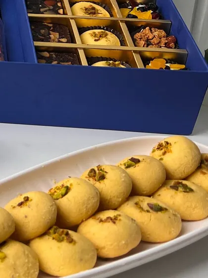 A platter of our freshly baked Elaichi Pista Nan Khatai, a traditional Indian shortbread cookie that is a popular addition to our Diwali hampers. These buttery cookies are delicately flavored with cardamom and topped with pistachio.