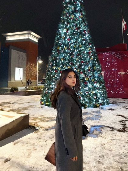 A classic portrait-style shot, looking back at the camera with the holiday lights creating a beautiful bokeh effect.