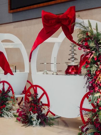 Elegant white carts adorned with large red bows and floral garlands, serving treats at the Wonderland party.