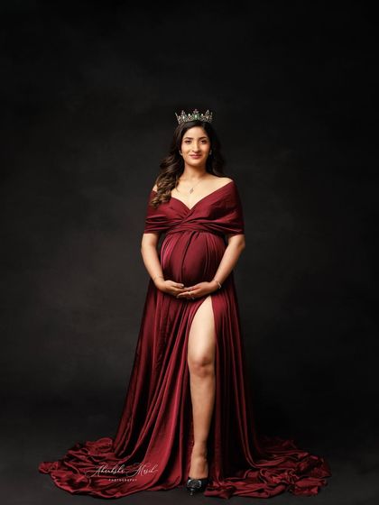 A powerful portrait of a queen on her throne. The rich red gown, the crown, and the dark background create a look of pure regality.
