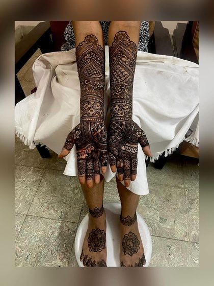 Full-arm and foot mehendi for a bride, showcasing symmetrical designs that are rich in detail. This is a perfect example of the grand, traditional bridal henna I specialize in.