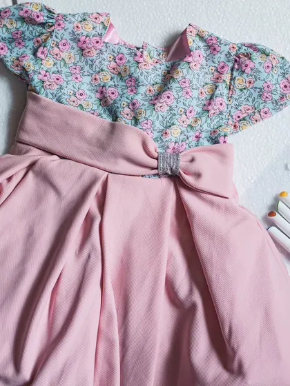 A beautiful pairing of a delicate floral print on the bodice with a solid dusty rose skirt. The box pleats create volume, and the bow with a silver buckle adds a modern touch.