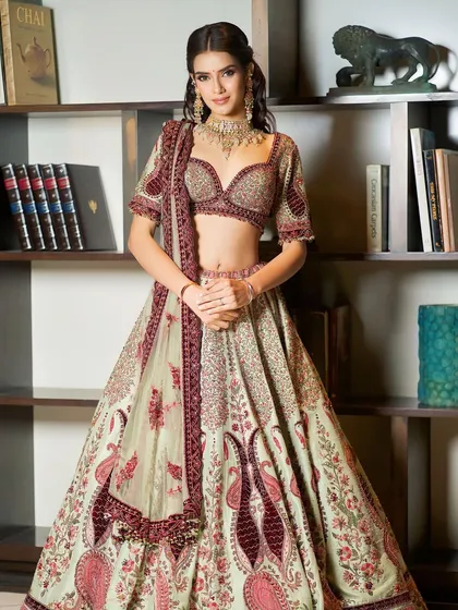 Regally adorned in soft, stunning hues. This full-length shot showcases a breathtaking designer lehenga, paired with soft, glamorous makeup.