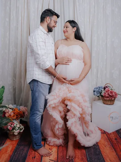 A classic standing pose for an expecting couple. This shot beautifully highlights the baby bump and the supportive connection between the partners in a light and airy studio setting.