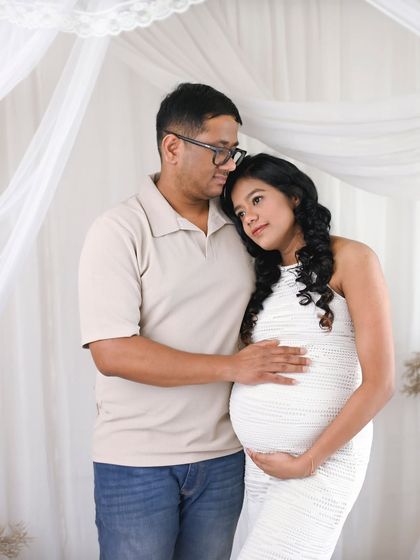 A pose of comfort and support, with her resting her head on his shoulder. This image beautifully portrays the partnership and love that supports their growing family.