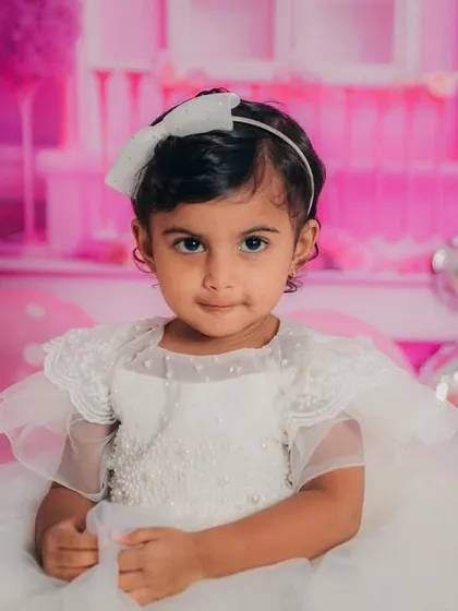 A calm and sweet portrait of the two-year-old, sitting patiently amidst the festive pink decorations of her Barbie-themed shoot.