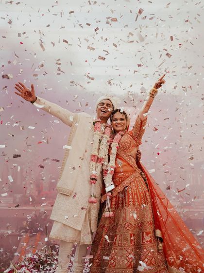 A moment of pure, unadulterated joy as the couple celebrates under a shower of confetti. Their arms are raised in triumph, a perfect picture of celebration at their Jodhpur wedding.