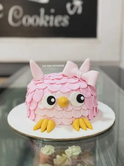 A close-up view of our adorable pink owl cake. The detailed feather work and large, expressive eyes make this a standout sculpted cake.