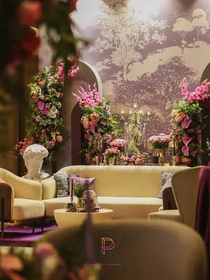 A wider view of the purple-themed lounge, where floral-draped archways and a soft wallpapered backdrop create a refined and comfortable space for guests to mingle.