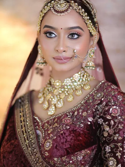The richness of a velvet maroon lehenga paired with a magnificent Kundan jewellery set. This close-up highlights the intricate details of the necklace and matha patti, creating a look of pure opulence and grandeur for a winter wedding.