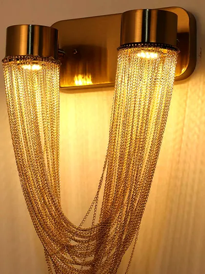 Details make the design. This close-up reveals the artistry of a wall sconce featuring delicate, cascading gold chains. It’s a perfect example of how I use texture and material to create lighting that is both a source of illumination and a piece of jewelry for your walls.