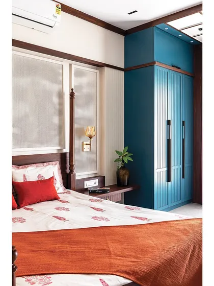 A view of the peacock blue wardrobe with its clean, fluted detailing and long, modern handles. The color choice adds a touch of drama and personality to the room.