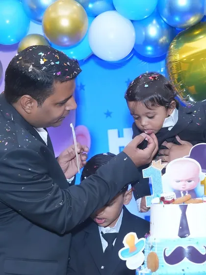 A sweet moment of a father feeding his son the first bite of his Boss Baby-themed birthday cake.