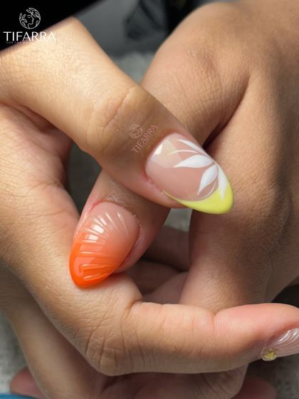 Beach please. A close-up of a hand-drawn white flower on a yellow-tipped nail and a 3D textured orange ombre nail.