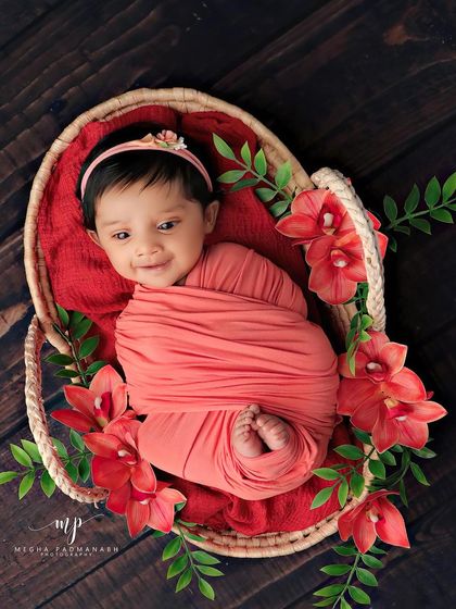 An absolutely joyful, open-mouthed smile from a baby in a coral-red wrap, nestled in a basket. These are the moments that make our job so rewarding.
