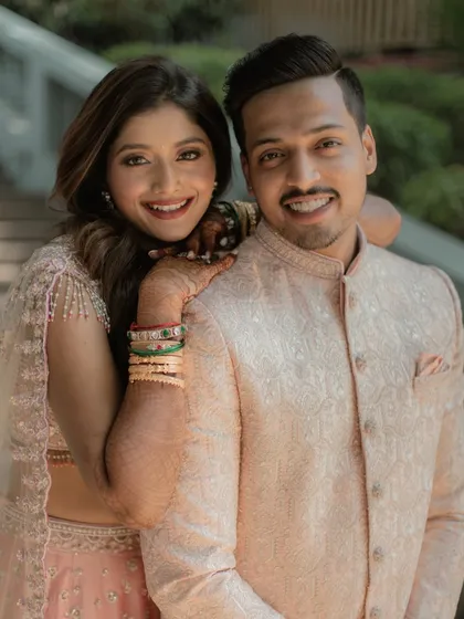 A bright and happy portrait of a couple in elegant pastel ethnic wear, perfect for an engagement or sangeet lookbook.