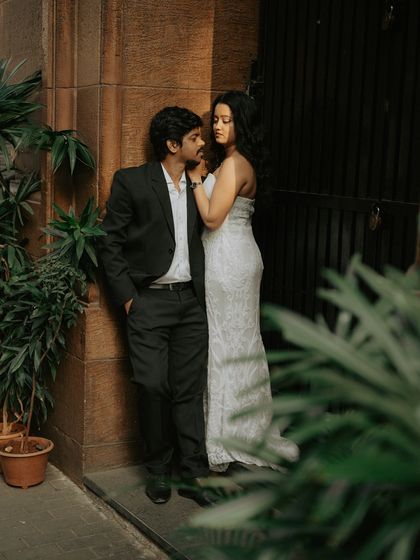 An intimate and moody portrait of the couple in a quiet corner, framed by greenery against the old stone architecture.