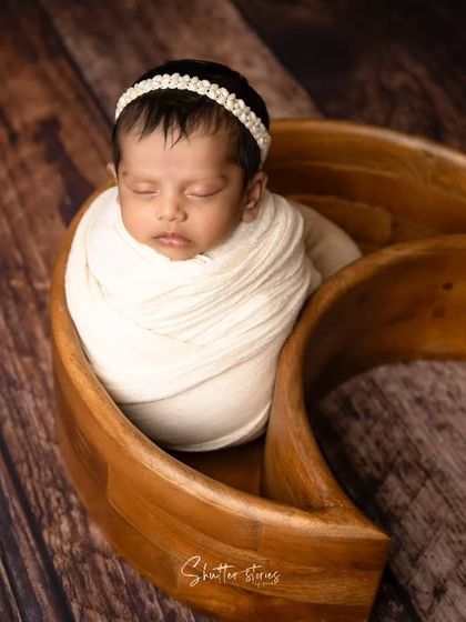 A minimalist portrait using a wooden moon prop and a simple white wrap, creating a clean and modern aesthetic.