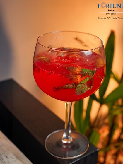 A refreshing red cocktail with muddled mint leaves, served in a large wine glass for a modern twist.