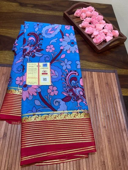 A vibrant blue floral Kalamkari print on a Mysore silk saree with a red border.