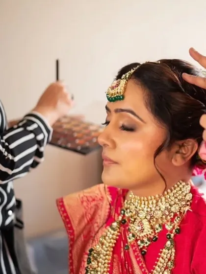 This bride's look was all about royal elegance. The makeup features a classic winged liner and a bold lip, paired with a traditional red saree and heavy jewelry for a truly regal appearance.