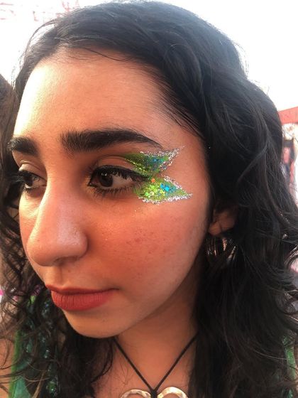 Butterfly wing inspired eye glitter in vibrant green and silver. This two-tone design adds a touch of fantasy to any festival outfit.
