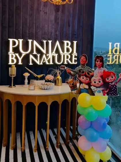 Even the gift or cake table can be part of the theme, as seen here with Cocomelon characters at the Punjabi by Nature venue.