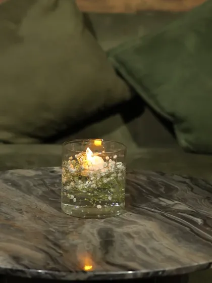 Even the smallest details matter. A simple glass candle holder filled with water and baby's breath adds a delicate and romantic touch to a side table or lounge area.