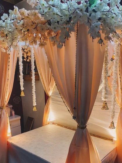 An elegant canopy with peach-colored drapes and a border of white cherry blossoms. The hanging bells add a traditional touch to this soft and beautiful design.