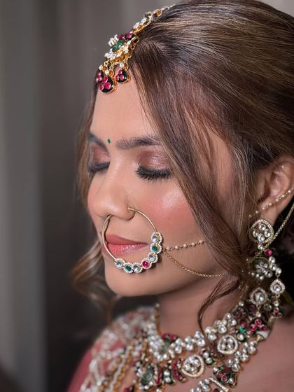 A close-up of a bride's intricate jewellery, including a multi-layered necklace with colorful stones, a large nath, and a floral hair bun. This is for the bride who loves detail.