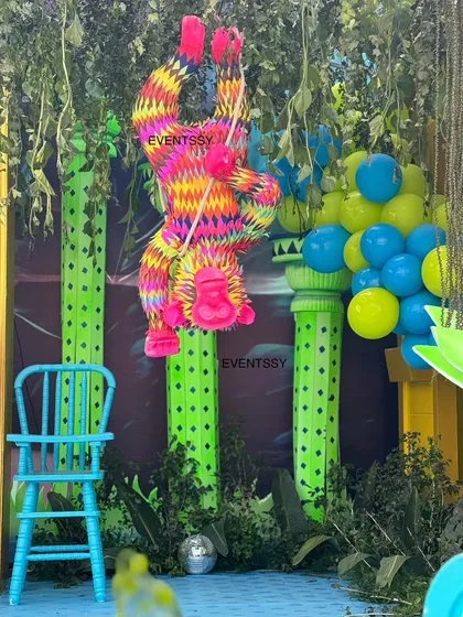 A colorful hanging monkey piñata adds a playful and interactive element to the neon jungle setup.