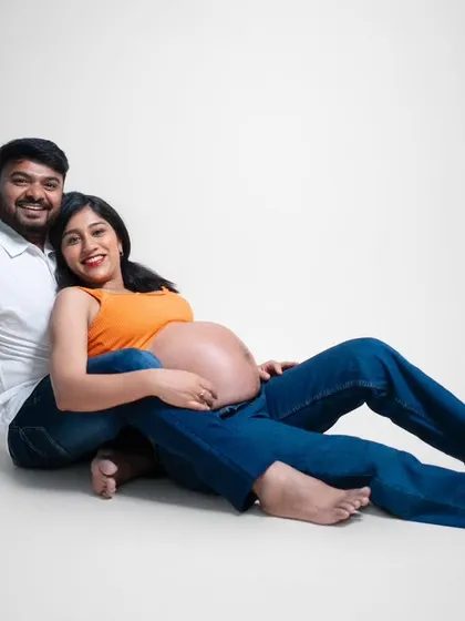 Comfortable, casual, and completely in love. This relaxed pose on the studio floor shows their easy intimacy. The simple white background keeps the focus entirely on their connection and the beautiful baby bump.