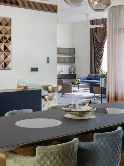 The dining area flows into the living room in this open-plan home, with a sophisticated color palette of blues, greys, and metallic accents.
