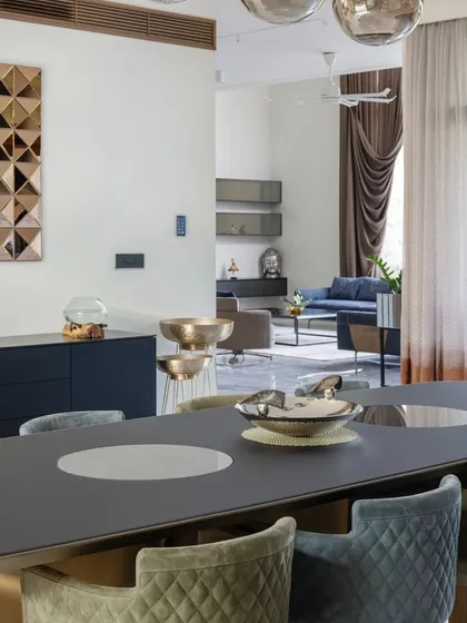 The dining area flows into the living room in this open-plan home, with a sophisticated color palette of blues, greys, and metallic accents.