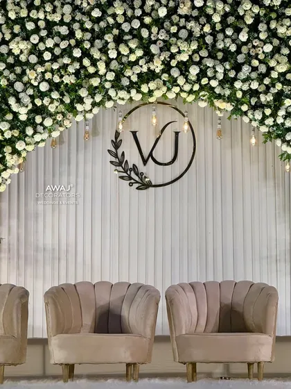 A detailed shot of the couple's monogram, surrounded by a cascade of white flowers and accented with vintage-style Edison bulbs for a warm glow.