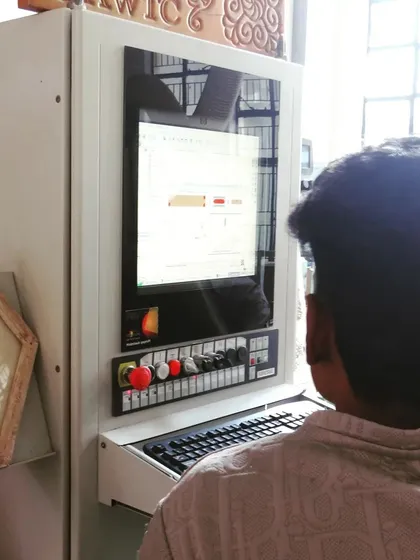 A student operates the control panel of a CNC machine. Our curriculum includes learning the software and interface to control the machine's every move.