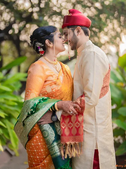 A beautiful, intimate moment between Omkar and Mansi, dressed in traditional Marathi attire for their engagement. The natural outdoor setting provides a soft, romantic backdrop.