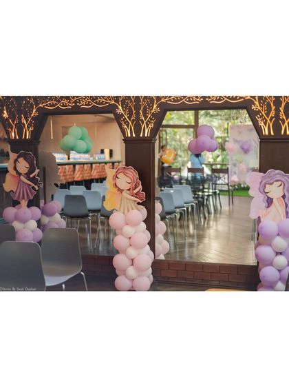 The entrance to a fairy-themed party, with balloon columns topped with cute fairy cutouts, welcoming guests into an enchanted space.