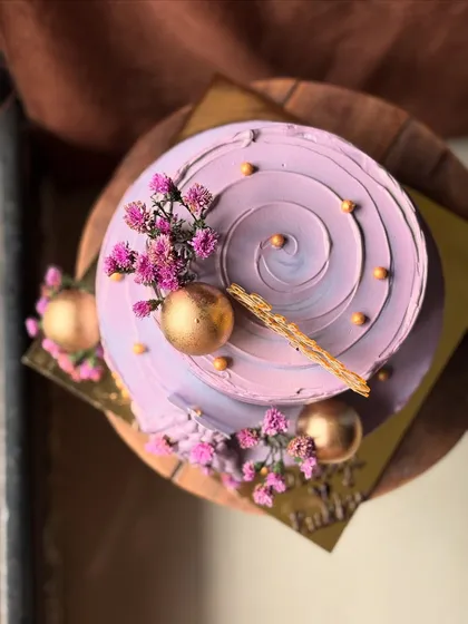 A dreamy lavender cake with purple swirls, gold spheres, and delicate dried flowers. Perfect for a romantic celebration like an engagement or anniversary.