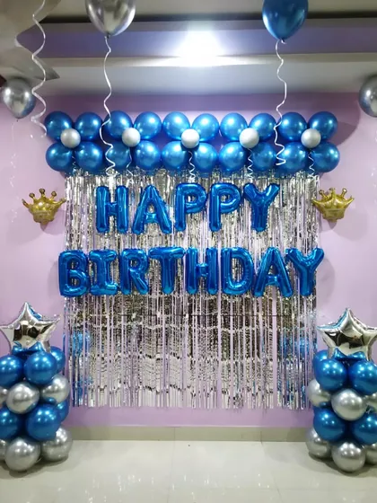 A simple yet elegant birthday backdrop in blue and silver. The decoration features balloon pillars and a flower-shaped balloon garland.