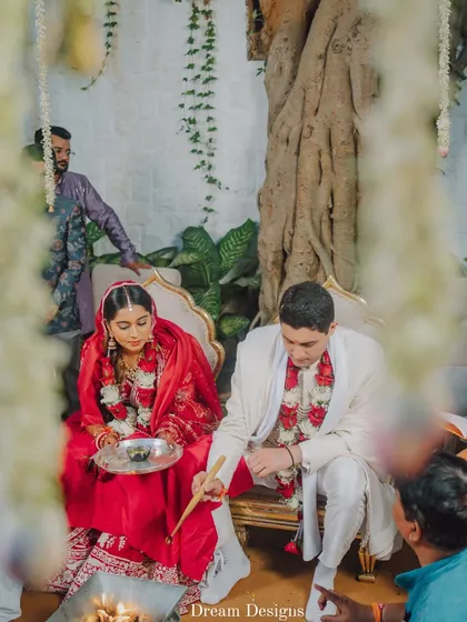 A quiet moment during the wedding rituals. The couple is seated within a custom-designed space under a banyan tree, with simple, elegant decor that keeps the focus on the sacred ceremony.