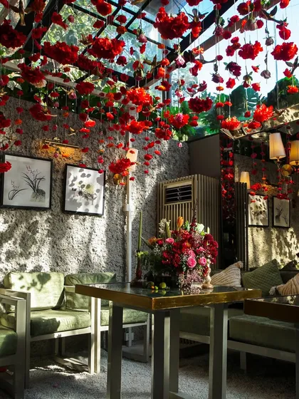 The Mehndi venue, with its ceiling of floating red carnations and cozy green sofas, created a vibrant yet intimate atmosphere for the celebration.