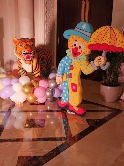 A life-sized clown cutout and a tiger prop used as decorative elements in a carnival party.
