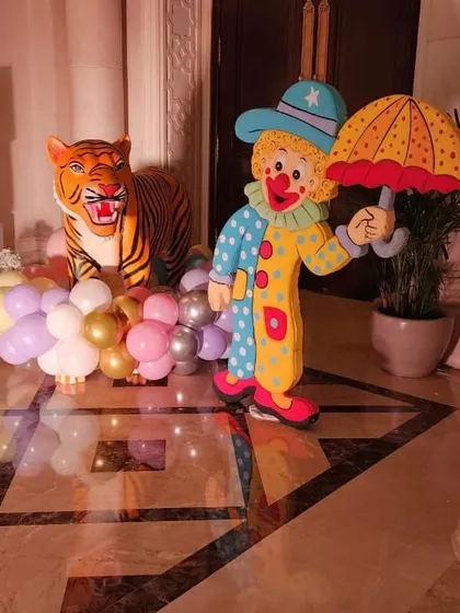 A life-sized clown cutout and a tiger prop used as decorative elements in a carnival party.
