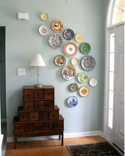 This image shows another take on a decorative plate wall, arranged in an organic, flowing pattern. It adds a touch of vintage charm and character to this entryway, complementing the antique-style wooden chest of drawers.