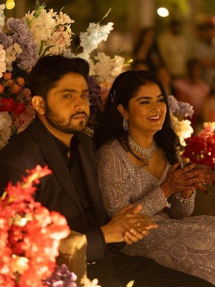 A beautiful shot of the couple on their Sangeet stage. The bride's makeup is glamorous but not overpowering, complementing the festive floral decor.