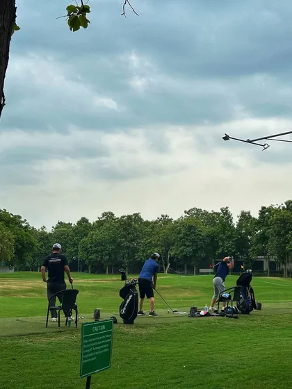 A group of three golfers practicing together, with their bags and equipment ready for a full session.