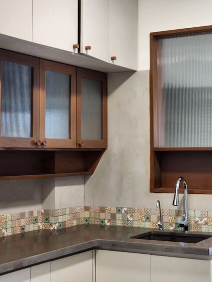 This kitchen corner features a mix of materials, including fluted glass, wood, and a colorful mosaic tile backsplash. The design balances functionality with a warm, handcrafted aesthetic.